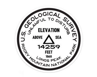 May include: A black and white round sticker with the text "U.S. GEOLOGICAL SURVEY UNLAWFUL TO DISTURB" around the edge. The centre of the sticker has the text "ELEVATION ABOVE SEA 14259 FEET 1868 LONGS PEAK ROCKY MOUNTAIN NATIONAL PARK".