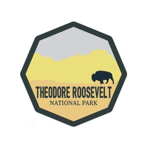 May include: A yellow and gray octagon-shaped sticker with a black silhouette of a bison walking across a yellow field. The text "Theodore Roosevelt National Park" is printed in black at the bottom of the sticker.