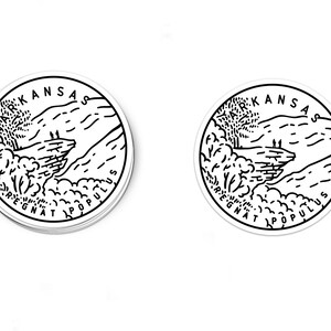 May include: Two black and white stickers with a circular design. The stickers feature a mountain range with the text "ARKANSAS REGNAT POPULUS" around the edge.