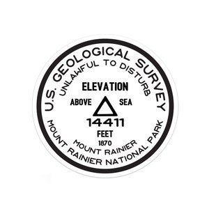 May include: A black and white round sticker with the text "U.S. Geological Survey" and "Unlawful to Disturb". The sticker also includes the text "Elevation Above Sea 14411 Feet 1870 Mount Rainier National Park Mount Rainier".