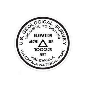 May include: A black and white round sticker with the text "U.S. GEOLOGICAL SURVEY UNLAWFUL TO DISTURB" around the edge. The center of the sticker has a triangle with the text "ELEVATION ABOVE SEA 10023 FEET HALEAKALA NATIONAL PARK HALEAKALA".