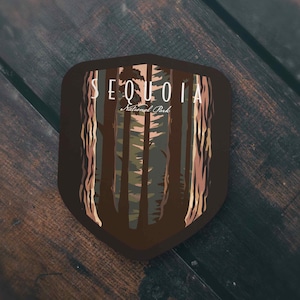 May include: A brown shield-shaped sticker with a forest scene and the text "SEQUOIA National Park".