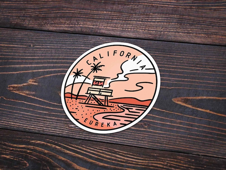 May include: A round sticker with a peach background featuring a line drawing of a lifeguard tower on a beach with palm trees and a cloud. The text "CALIFORNIA" is written in a circle around the top of the sticker and "EUREKA" is written at the bottom.