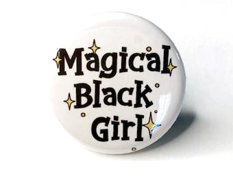 Pode incluir: Botão branco com o texto "Magical Black Girl" em letras pretas com detalhes de glitter dourado.