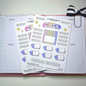 May include: Two planner sticker sheets with a pink border, featuring the text "2026" in a gradient design, along with the words "GOALS" and "VISION BOARD." The stickers include illustrations of books and stars, designed for planning and goal setting.