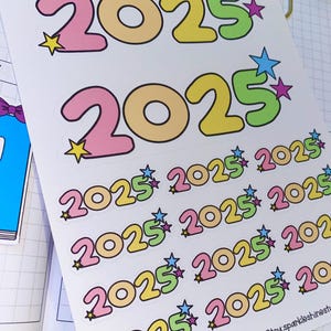 May include: A sheet of colorful 2025 stickers with a star design. The stickers are in pink, yellow, green, and blue. The text "2025 LABELS" is at the bottom of the sheet.