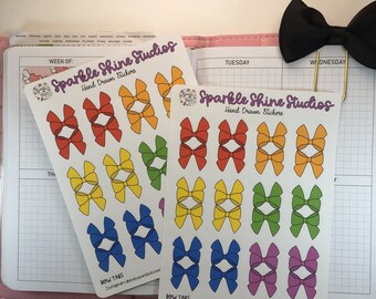 May include: Two sheets of rainbow colored bow stickers with the text "Sparkle Shine Studios Hand Drawn Stickers" and "BOW TABS" on each sheet. The text "RTBS-002" is on the bottom right corner of the sheet.