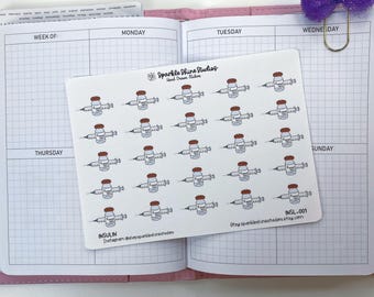 May include: A sheet of white stickers featuring small illustrations of insulin syringes. The stickers are arranged in a grid pattern and are labeled "INSULIN." The stickers are on an open planner with grid lines. A purple bow paperclip is attached to the planner.