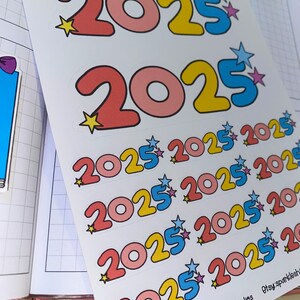 May include: A sheet of stickers with multiple colorful 2025 stickers. The stickers are in a variety of colors, including pink, yellow, blue, and white. The stickers are arranged in rows and columns, and each sticker has a star on it.