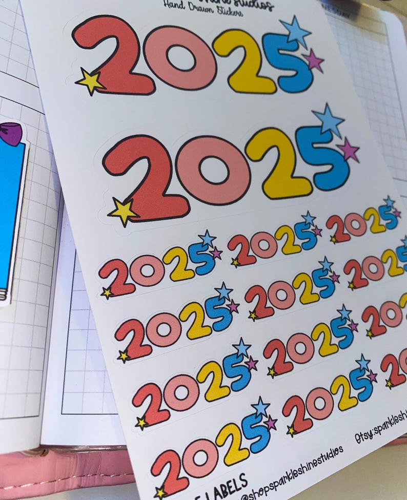 May include: A sheet of stickers with multiple colorful 2025 stickers. The stickers are in a variety of colors, including pink, yellow, blue, and white. The stickers are arranged in rows and columns, and each sticker has a star on it.