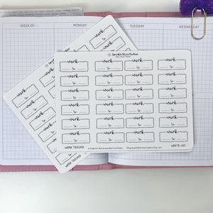 May include: Two sheets of white planner stickers with black text. Each sticker has the word "work" and a space to write "to". The stickers are on a pink planner, with a purple bow paper clip.