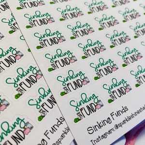 Puede incluir: Una hoja de pegatinas con el texto "Sinking Fund" en letras verdes. Las pegatinas muestran una alcanc&iacute;a, bolsas de dinero y monedas. El texto "Sinking Funds" tambi&eacute;n est&aacute; escrito en letras negras en la parte inferior de la hoja. El texto "Instagram:@sparkleshinestudios" est&aacute; escrito en letras negras debajo del texto "Sinking Funds".