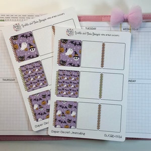 May include: Two sheets of Halloween themed planner stickers with a purple background and a pattern of bats, ghosts, pumpkins, and cats. The stickers are designed to be used in a planner or journal. The text on the stickers reads "Super Secret Journaling" and "SJCRD-0016".