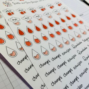 Pu&ograve; includere: Un set di adesivi per il monitoraggio del ciclo mestruale con un design a goccia rosa e rossa. Gli adesivi hanno testo che recita "crampi", "nausea", "mal di testa", "affaticamento" e "tracker del ciclo".