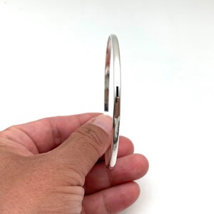 May include: A simple silver bangle bracelet with a smooth, polished finish.