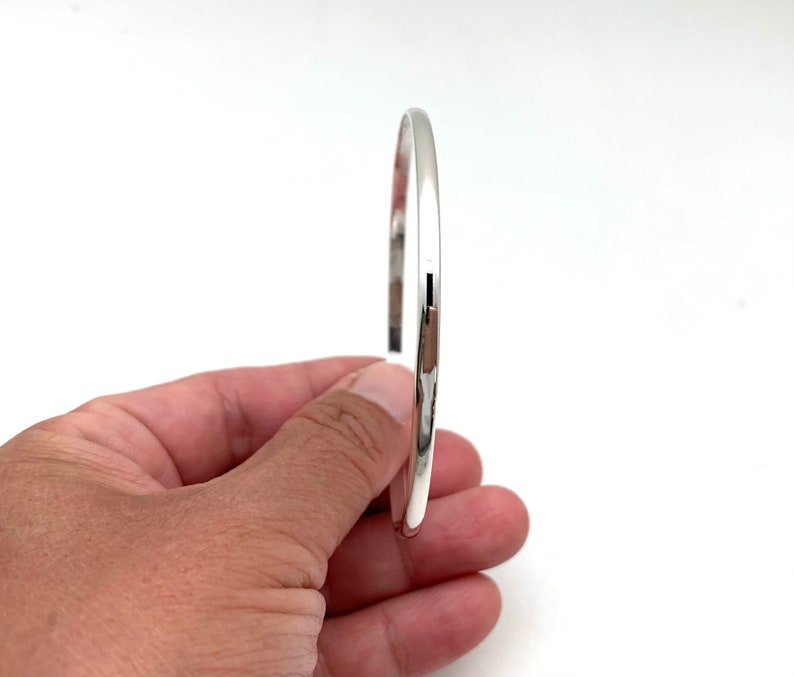 May include: A simple silver bangle bracelet with a smooth, polished finish.