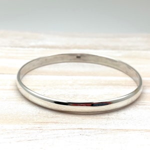 May include: A silver bangle bracelet with a smooth, polished finish.
