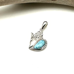 May include: A silver pendant featuring a heart-shaped blue and white gemstone with a detailed floral design.