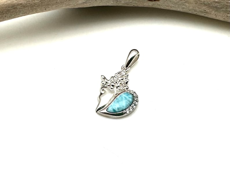 May include: A silver pendant featuring a heart-shaped blue and white gemstone with a detailed floral design.