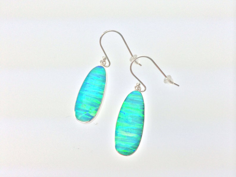 Peut inclure: Une paire de boucles d'oreilles pendantes en argent avec des pierres d'opale ovales vertes et bleues.