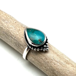 Peut inclure: Une bague en argent avec une pierre turquoise en forme de larme sertie dans une bélière perlée.