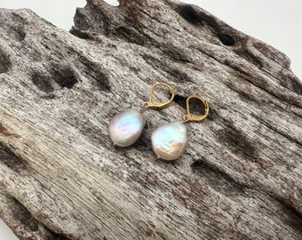 Può includere: Un paio di orecchini pendenti in oro con un ciondolo a forma di lacrima di perla. Le perle sono di un bianco morbido e iridescente.