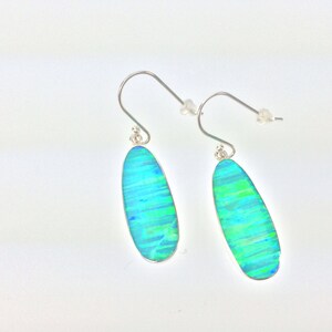 Peut inclure: Une paire de boucles d'oreilles pendantes en argent avec des pierres d'opale ovales bleues et vertes.