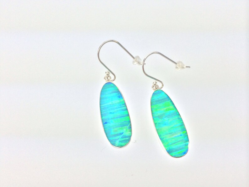 Peut inclure: Une paire de boucles d'oreilles pendantes en argent avec des pierres d'opale ovales bleues et vertes.