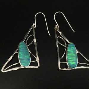 May include: A pair of silver earrings with a green opal stone set in a triangular frame.