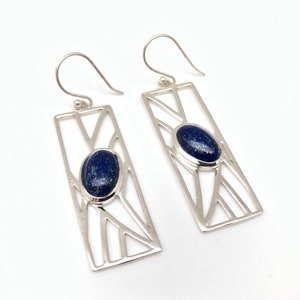 May include: A pair of silver earrings with a geometric design and a blue lapis lazuli stone in the center of each earring.