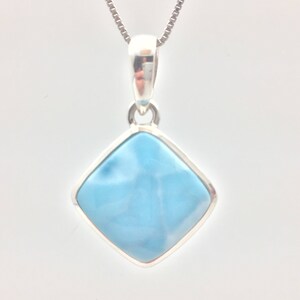 May include: A silver pendant necklace with a square shaped blue gemstone.