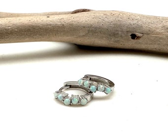 May include: A pair of silver hoop earrings with a row of white opal stones set in each hoop.