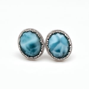 Könnte beinhalten: Ein Paar silberne Ohrringe mit blauen und weißen, irisierenden Edelstein-Cabochons.