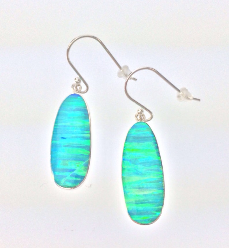 Peut inclure: Une paire de boucles d'oreilles pendantes en argent avec des pierres d'opale ovales vertes et bleues.