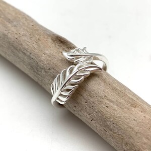 May include: A silver ring with a delicate feather design. The ring is adjustable and can be worn on any finger.
