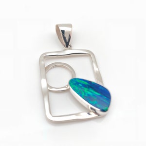 May include: A silver pendant featuring a teardrop-shaped blue opal set within a square frame with a circle cutout.