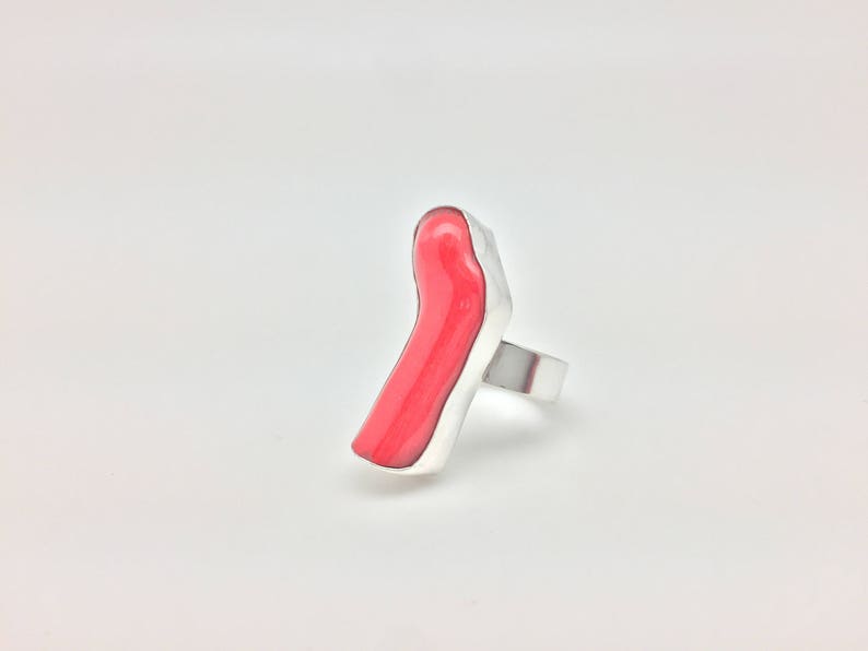 May include: A silver ring with a bright red, abstract, resin-like stone.