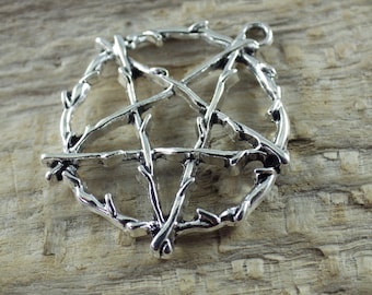 May include: Silver pendant in the shape of a pentagram, made of twisted branches. The pendant is on a wooden surface.