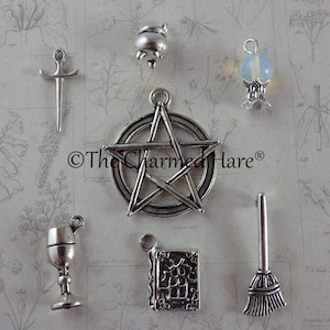 May include: A selection of silver charms with a mystical theme. Includes a pentagram, a cauldron, a sword, a chalice, a book, a broom, and a crystal ball. The Charmed Hare logo is visible.