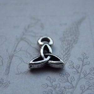 Puede incluir: Encanto de plata en forma de nudo celta, un s&iacute;mbolo tradicional de amor, amistad y unidad.