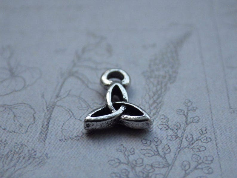 Puede incluir: Encanto de plata en forma de nudo celta, un s&iacute;mbolo tradicional de amor, amistad y unidad.