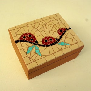 May include: A wooden box with a mosaic tile top. The mosaic design features three red and black flowers with turquoise leaves on a beige background.