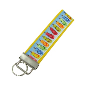 May include: A yellow key chain with a blue and white pattern of flip flops. The key chain has a silver metal key ring.
