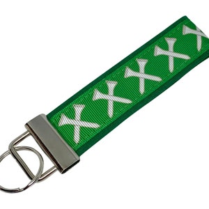 May include: Green key chain with a silver key ring and a white golf tee design.