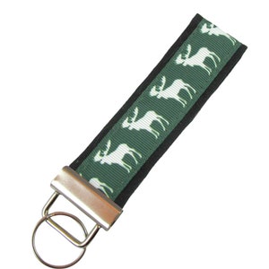 May include: A green and white key chain with a silver key ring. The key chain features a repeating pattern of white moose silhouettes on a dark green background.