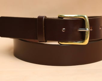 May include: A brown leather belt with a brass buckle. The belt is folded in half and the buckle is visible in the center of the image.