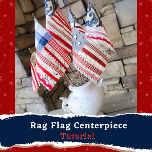 May include: A white ceramic vase with a red, white, and blue rag flag centerpiece. The flags are made of fabric and lace and are decorated with red, white, and blue ribbon. The vase is decorated with white stars. The text "Rag Flag Centerpiece Tutorial" is displayed below the image.