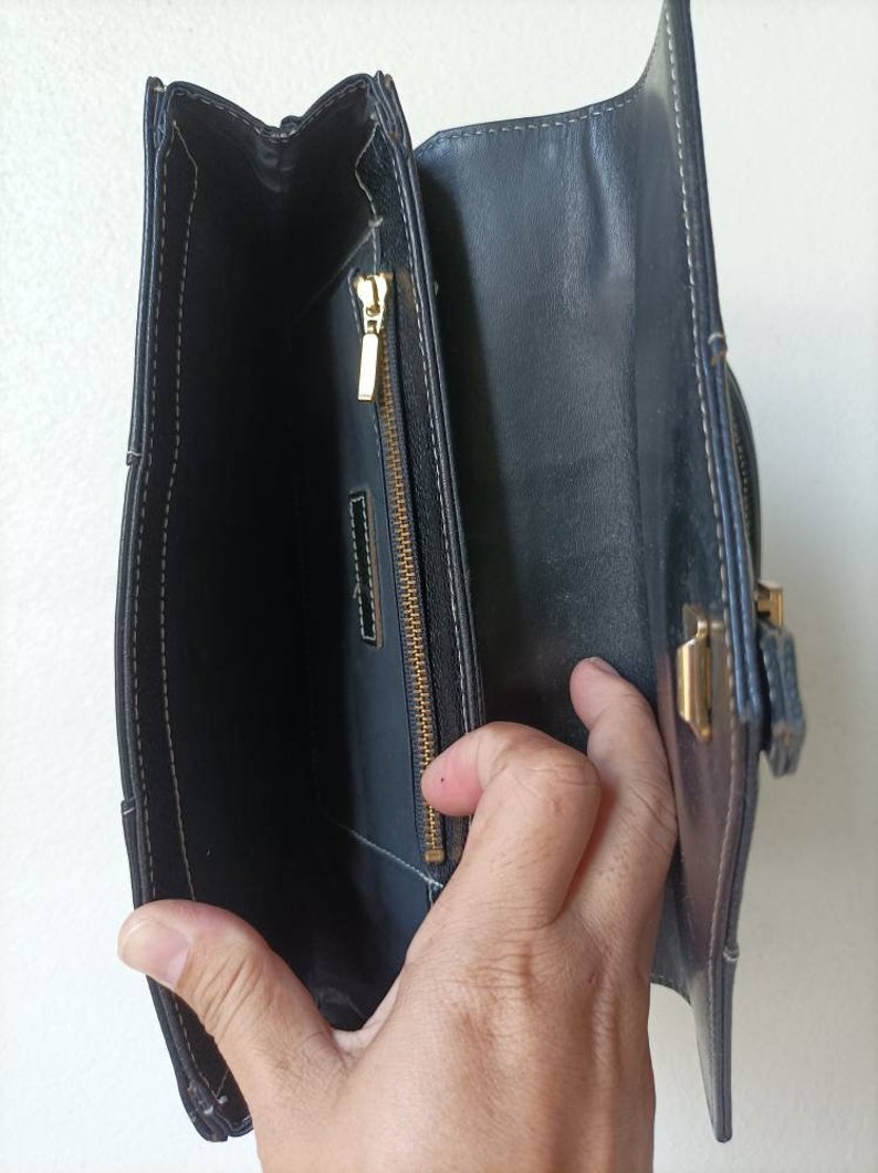May include: A black leather purse with a gold zipper and clasp. The purse is open and the inside is visible.