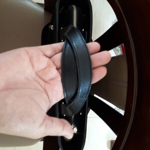 K&ouml;nnte beinhalten: Eine schwarze Ledertasche mit einem oberen Henkel und einem Rei&szlig;verschluss.