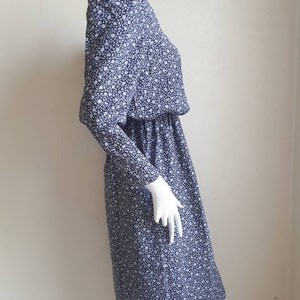 May include: A blue and white floral print dress with long sleeves and a gathered waist.